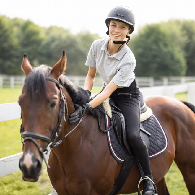 female-horseman-riding-brown-thoroughbred-horse-in-summer